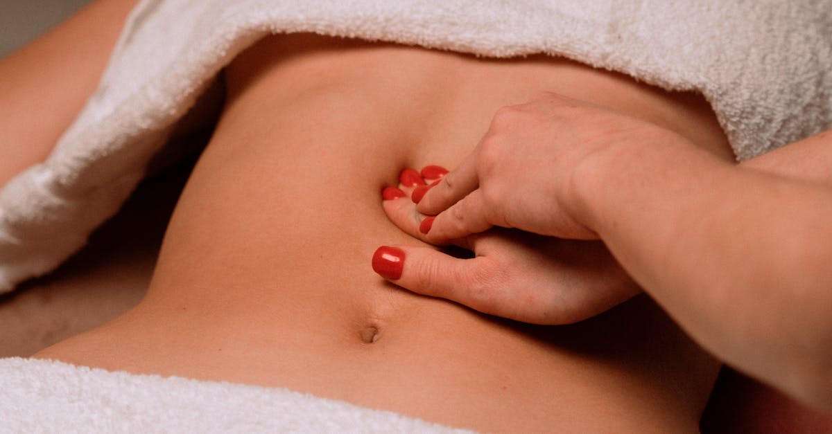 A soothing massage on a woman's abdomen with painted nails, creating a serene spa atmosphere.